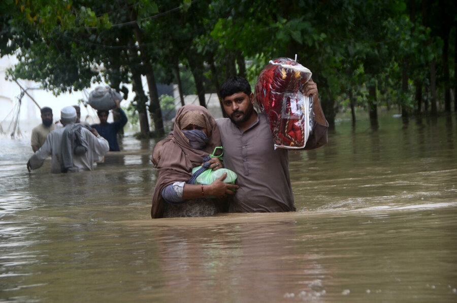 En kvinne og mann går ned en oversvømmet gate i Peshawar, Pakistan. Foto: Andolu via AFP/Hussain Ali.