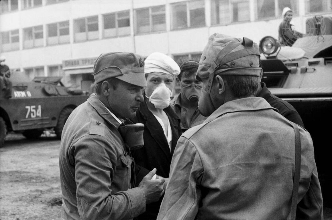 Bildet viser soldater prate sammen. De er ikledd gassmasker for å unngå å puste inn radioaktivt materiale.