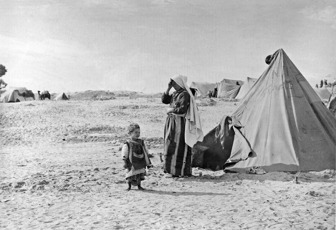 En palestinsk kvinne står sammen med barnet sitt utenfor teltet sitt i flyktningleiren Khan Younis i 1949. Foto: UN Photo