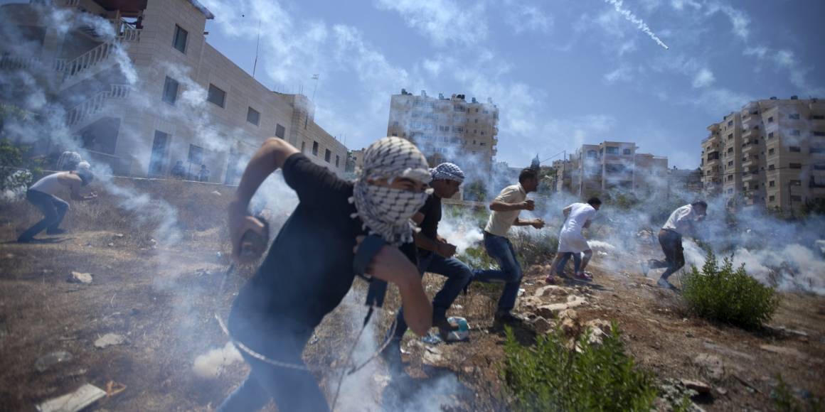 Palestinere demonstrerer mot krigen på Gaza i august 2014, og blir møtt med tåregass. Foto: AP/Majdi Mohammed